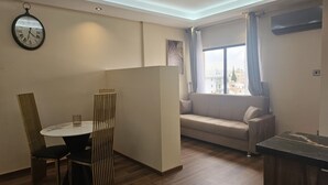 Una sala de estar moderna con una mesa redonda, dos sillas, un sofá y una ventana con cortinas.