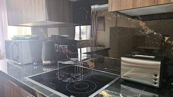 A kitchen with a black countertop, a stove, a toaster, and a coffee maker.
