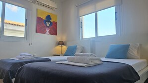 Ett hotellrum med två sängar, en tavla på väggen och stora fönster.