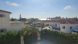 Ett bostadsområde med hus som har röda tegeltak, en klar himmel och utsikt över havet.