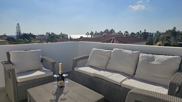 Relax on the rooftop with a wicker sofa set and enjoy the view of the surrounding houses and palm trees.