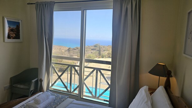 Ein Hotelzimmer mit großem Fenster mit Blick auf einen Pool und eine Berglandschaft.