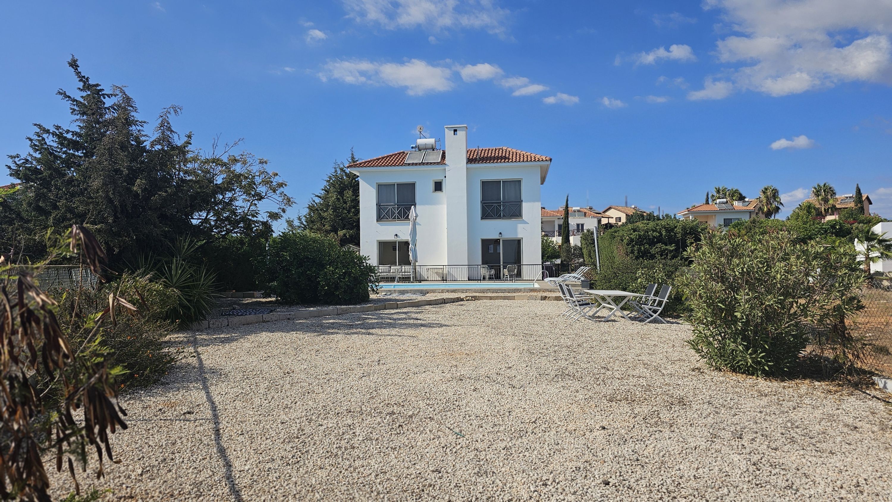 A two-story building with a tiled roof, a swimming pool, and outdoor seating.