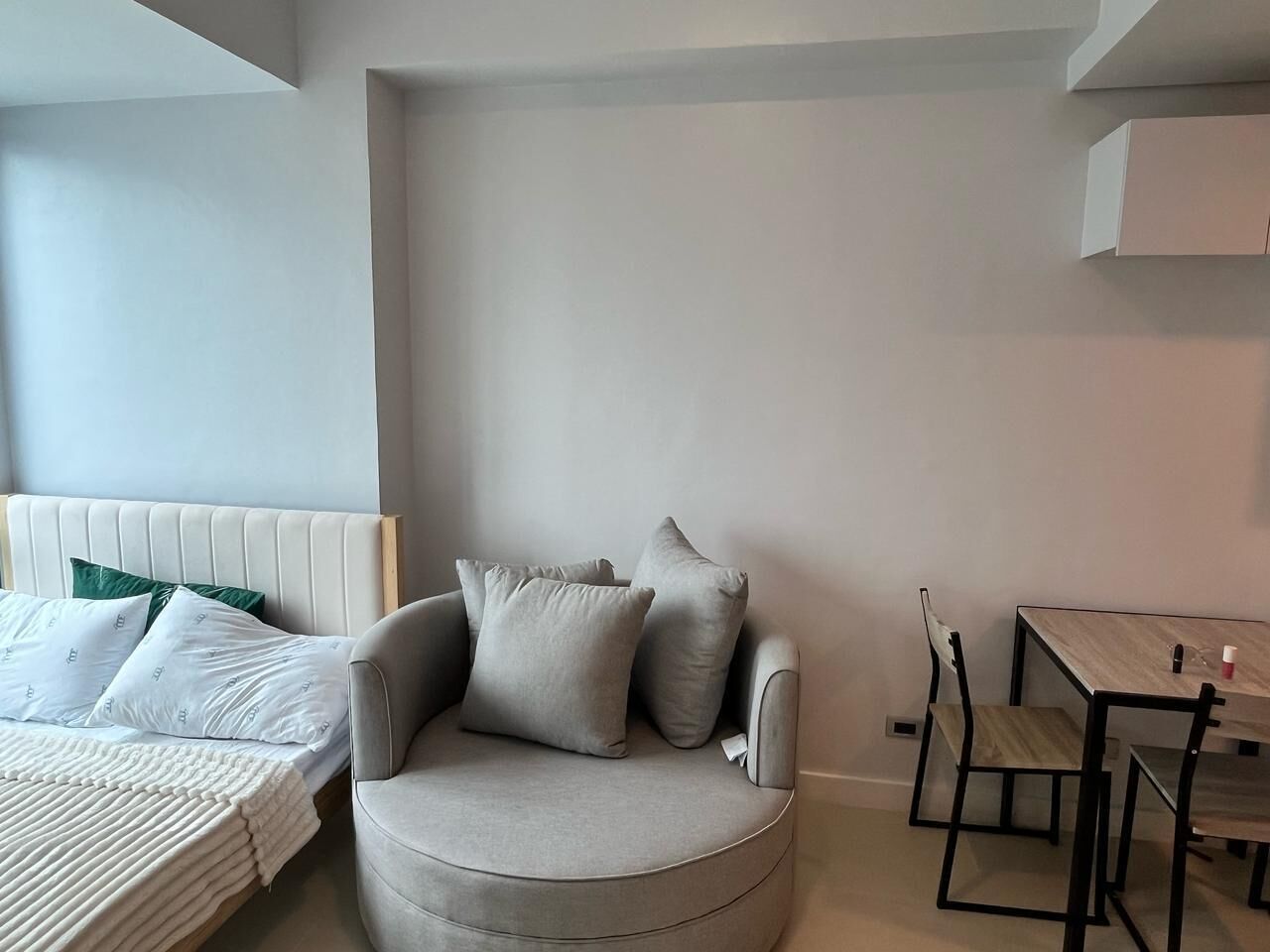 Une chambre moderne avec un lit, un fauteuil gris, une table en bois et une chaise.