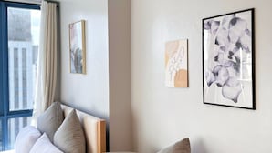 A modern hotel room with a curved sofa, a bed with white linens, and two framed artworks on the wall. - Cozy studio with Pool and fitness room in enjoyable Cebu City (Cebu City)