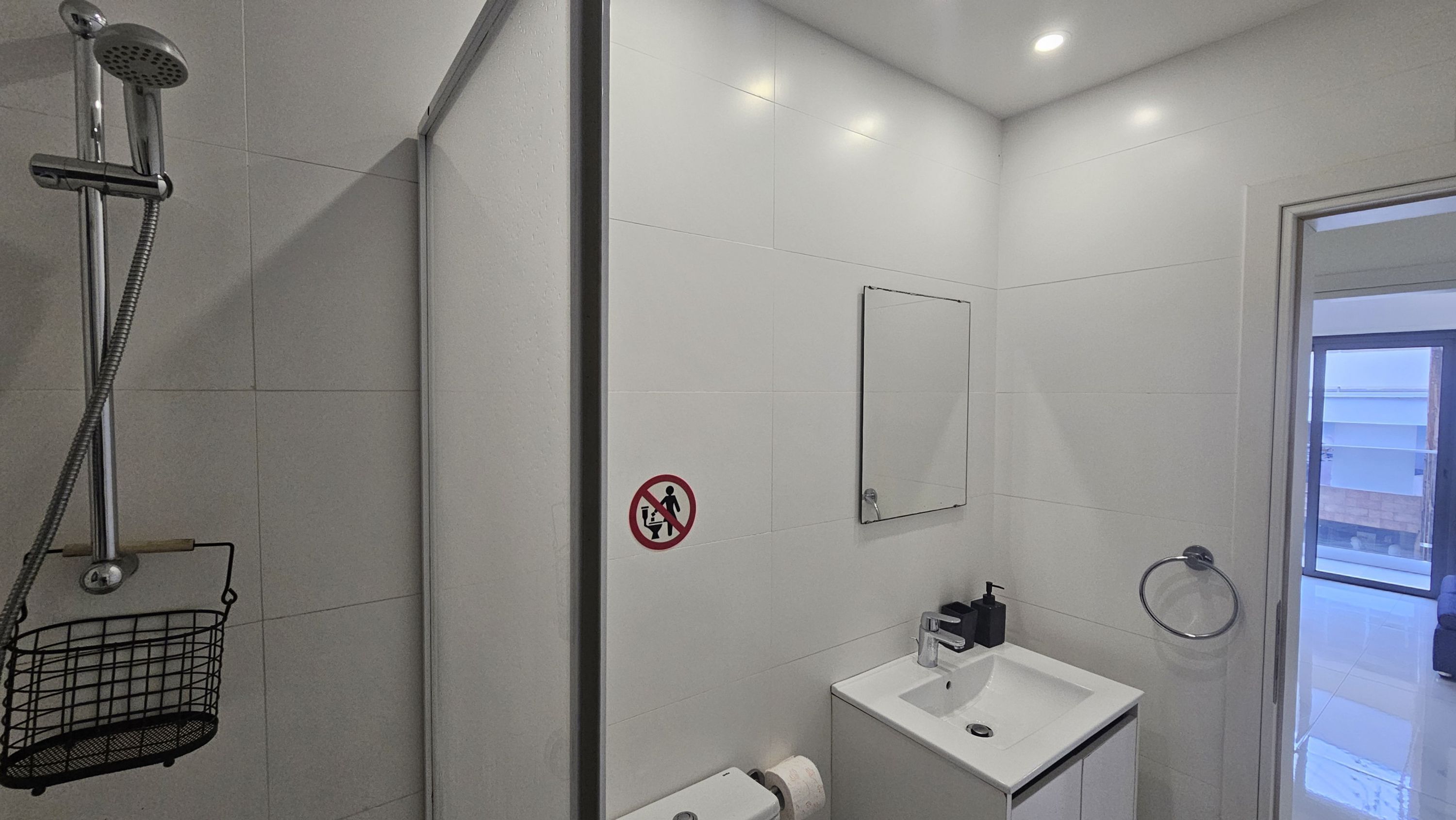 A modern bathroom with a shower, sink, and toilet.