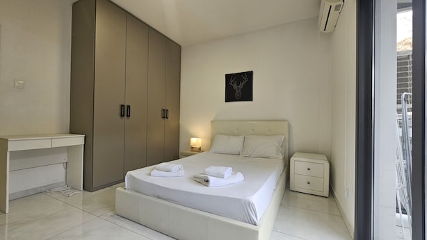 Une chambre à coucher comprenant un lit, une table de chevet, un bureau et une armoire.
