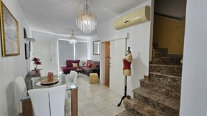 A spacious living area with a dining table, a sofa, and a staircase. - 27 NIC - Stay Alex s House (Strovolos)