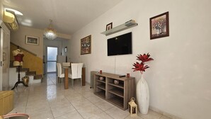 A spacious living area with a dining table, chairs, a TV, and decorative items. - 27 NIC - Stay Alex s House (Strovolos)