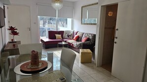 A modern living room with a red sofa, a glass dining table, and a view of the outdoors through large windows. - 27 NIC - Stay Alex s House (Strovolos)