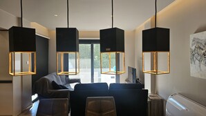 A modern living room with a sofa set, a flat-screen TV, and pendant lights.