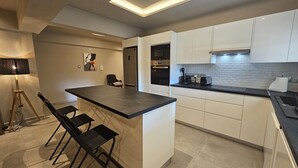 A modern kitchen with a central island, white cabinetry, and a black countertop.