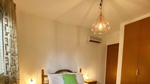 A neatly made bed with a green bedspread and two towels, a wooden headboard, a hanging light fixture, and a nightstand with a lamp. - 43 MND - Stay Meadow Vista Apartment (Mandria)