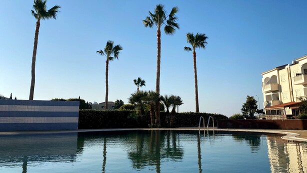 A clear pool with reflections of palm trees and a building with balconies. - 43 MND - Stay Meadow Vista Apartment (Mandria)