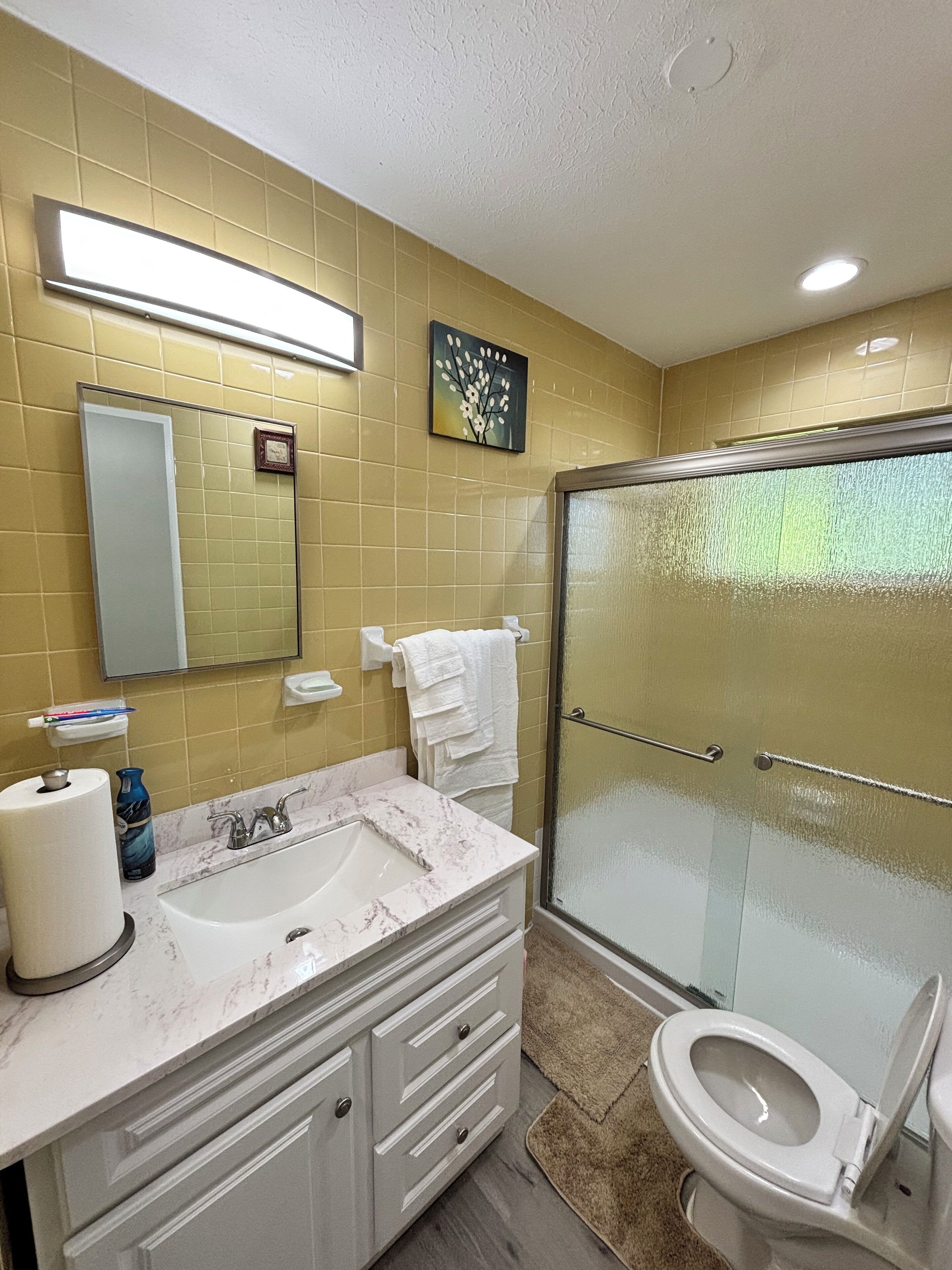 A bathroom with a marble sink, a toilet, and a glass shower enclosure.
