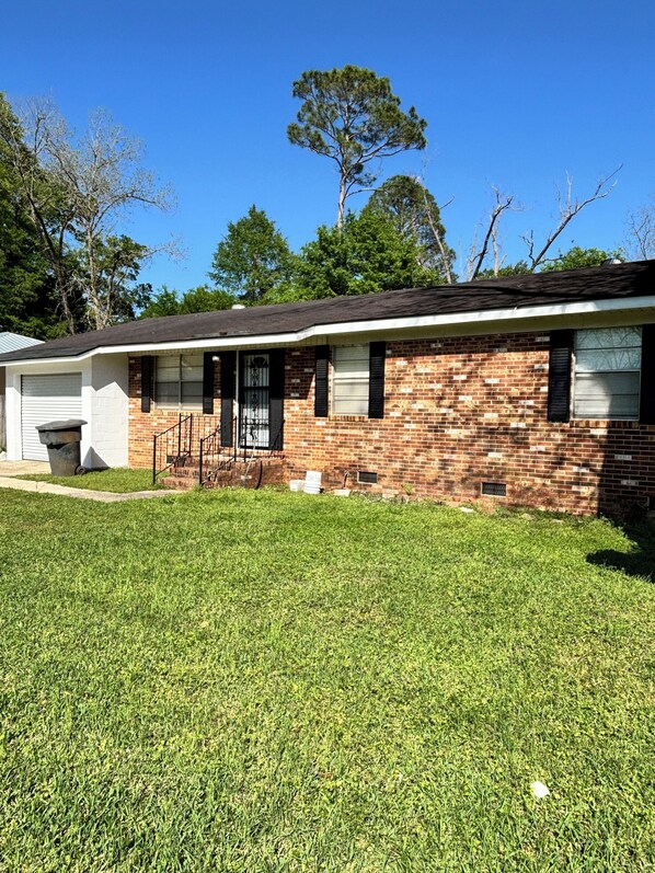 A single-story brick house with a front yard and a garage. - Charming 3-bedroom building with WiFi, AC, Garage and porch in tranquil Cuthbert (Cuthbert)