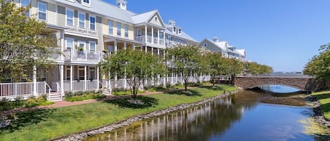 A row of waterfront hotel buildings with balconies, a stone bridge, and a calm river.