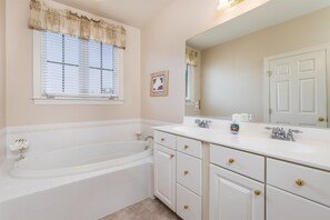A bathroom with a bathtub, a sink, and a mirror.