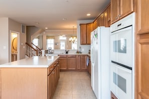 Een keuken met houten kastjes, een wit aanrechtblad en een inbouwoven.