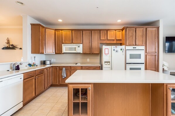 A modern kitchen with wooden cabinets, a microwave, a refrigerator, and an oven.