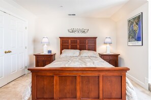 A bedroom with a wooden bed, two bedside tables with lamps, a decorative wall piece, and a framed map on the wall.