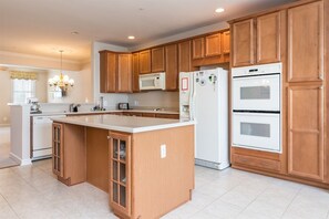 A kitchen with wooden cabinets, a central island, a microwave, a refrigerator, and an oven. - Sunset Island 3 Fountain Drive West (Ocean City)
