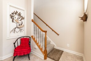 Un escalier avec une rampe en bois et une chaise rouge au premier plan.