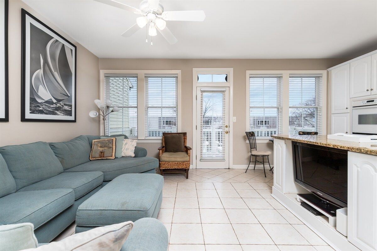A living room with a sofa, a television, and a kitchen area with cabinets and a microwave.