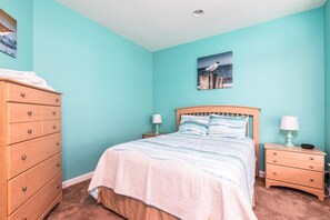 Ein Schlafzimmer mit einem Bett, zwei Nachttischen, einer Kommode und einem Wandbild.