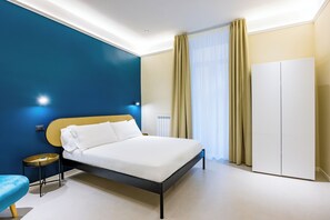 Relax in a spacious room with a large bed, white bedding, and a blue accent wall.