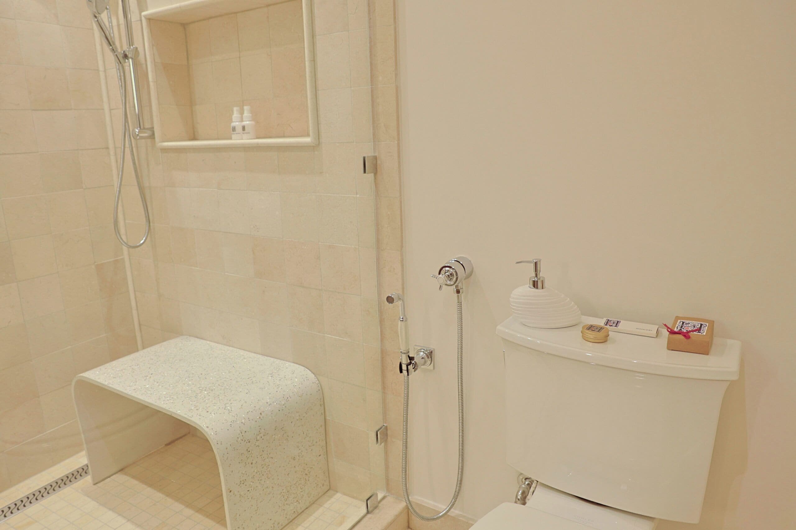 A bathroom with a shower, a toilet, and a small bench.