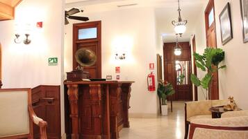 A reception area with a wooden desk, a mirror, and a potted plant.