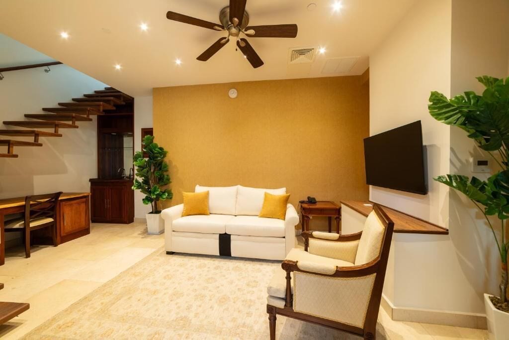 A modern living room with a white sofa, wooden coffee table, and a ceiling fan.