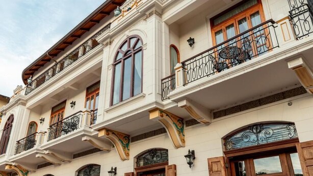 Un edificio de varios pisos con balcones ornamentados, ventanas grandes y molduras decorativas.