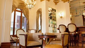 Una habitación lujosa con candelabros ornamentales, un espejo grande y una zona de bar con estantes llenos de botellas.