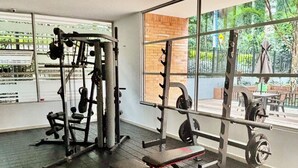 A gym with weightlifting equipment and large windows offering a view of greenery outside. - Poblado Family and Friend Bachelor Retreat (Medellín)