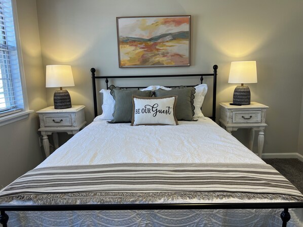 A neatly made bed with a striped blanket, two bedside tables with lamps, and a painting on the wall. - Spacious 4Bed/2Bath:Newly Refurbished: 2 Floors w/2 Living Rooms: 15 Min to GOLF (Augusta)