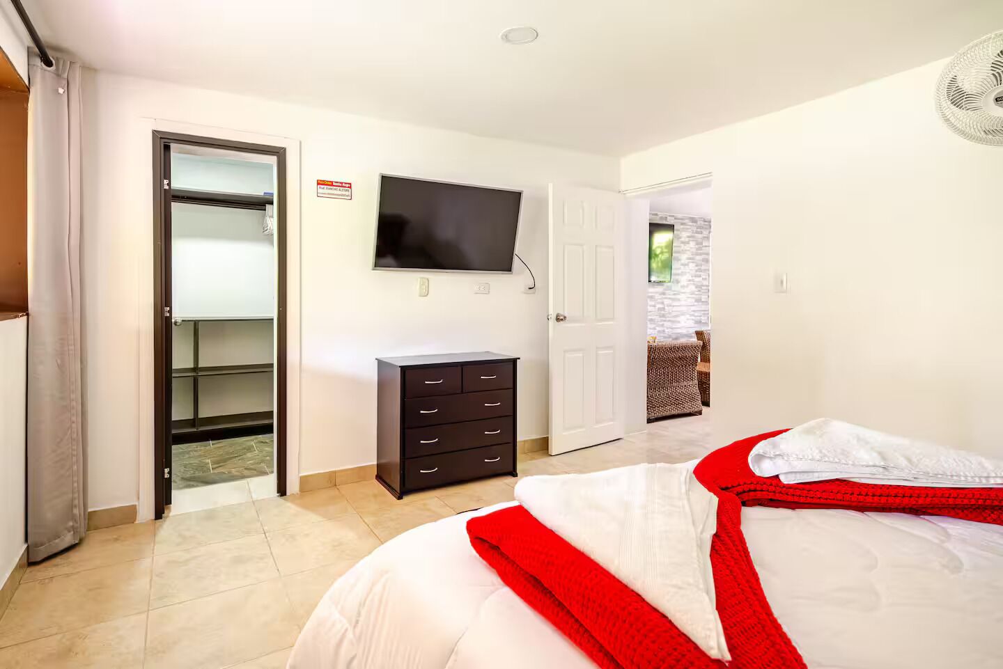 A bedroom with a bed, a TV, a wardrobe, and a door leading to a balcony.