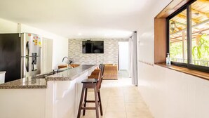 A modern kitchen with a granite countertop, stainless steel appliances, and a stone backsplash. - Relax, Play, Celebrate – Chalet Rancho Alegre (Quindío)