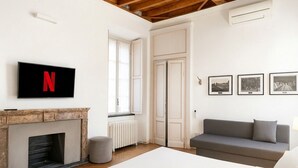 Een moderne kamer met een open haard, een grijze bank, een aan de muur bevestigde televisie en lijstwerken aan de wand.