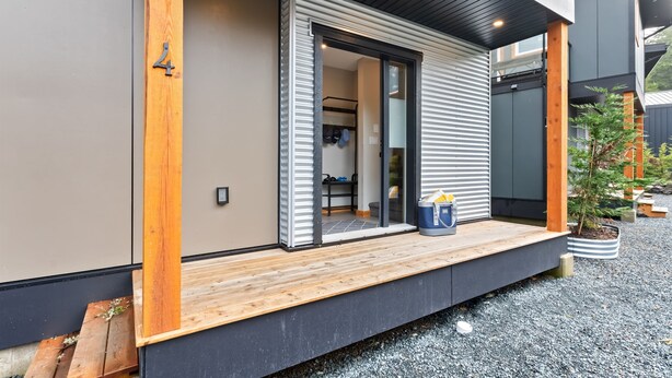 Una casa moderna con terraza de madera, puerta corrediza de vidrio y un pequeño jardín.