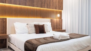 Un lit bien fait, avec des draps blancs, un plaid marron et une serviette pliée posée sur le côté.