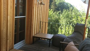 Eine Holzterrasse mit einer Couch, einem kleinen Tisch und einer Bank.