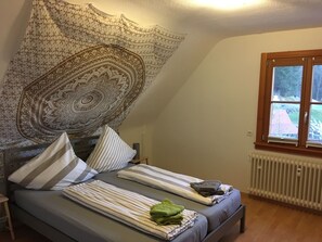 A bedroom with a bed, pillows, a blanket, a radiator, and a window with a view. - SichtWeiten-Auszeit (Seebach)