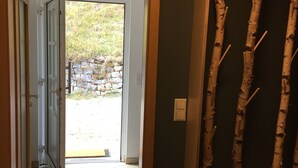 Eine geöffnete Tür, die zu einem gefliesten Bereich mit einer Steinsäule führt.