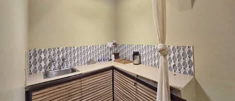 A kitchen with a sink, a coffee maker, and a patterned backsplash.