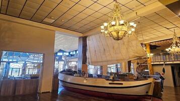 A spacious interior with a large ship model, chandeliers, and a reception area.