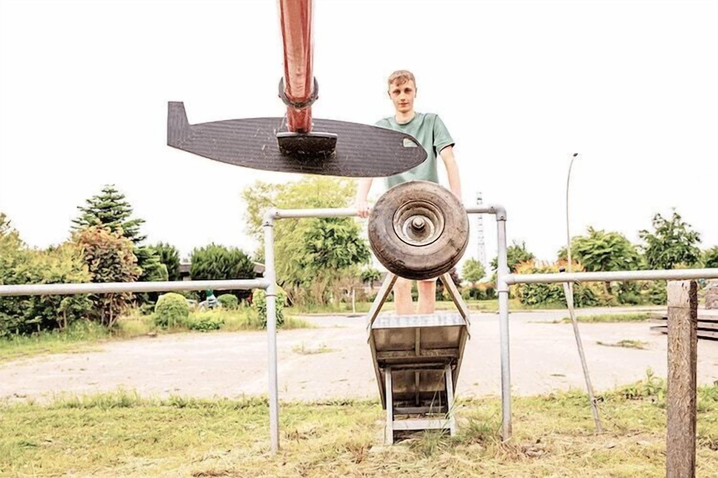 Eine Person steht neben einer Maschine mit einem großen Rad und einer Plattform.