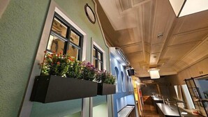 A corridor with a built-in planter with flowers, a clock on the wall, and a kitchen area with a counter and sink.