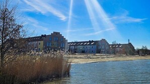 A riverside view with buildings, a clear sky, and a distant light source.